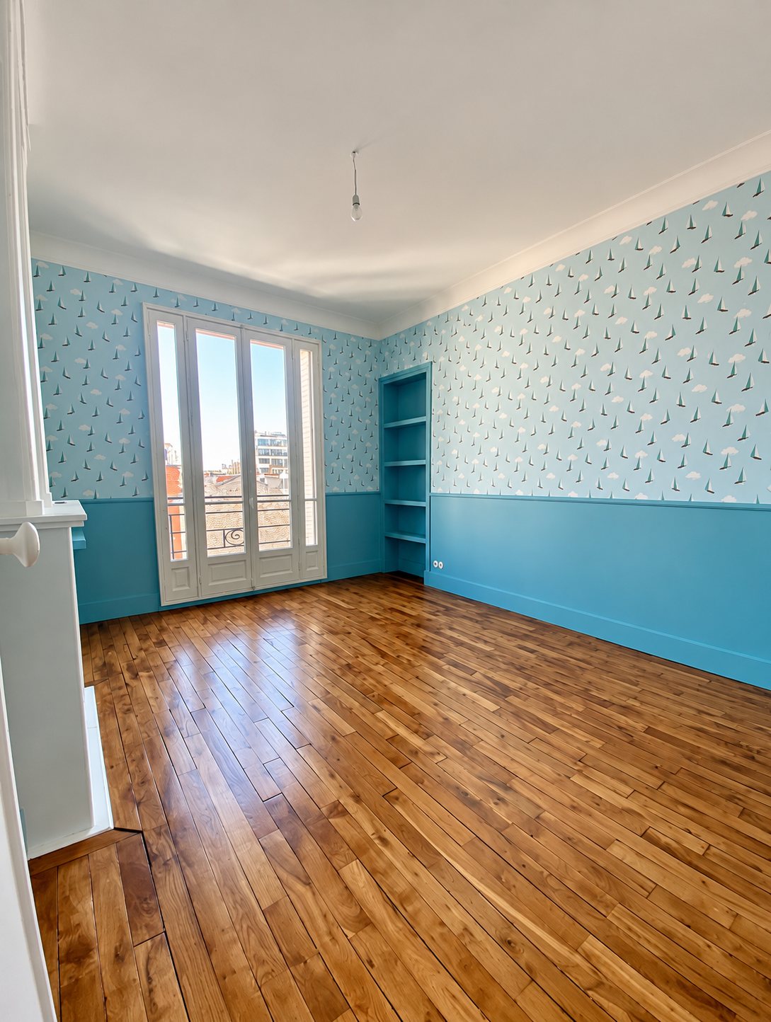 Chambre rénovée avec papier peint bleu à motifs et parquet